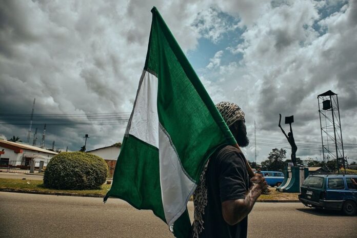 A protester holding the Nigerian flag walks the streets during demonstrations in Port Harcourt, Nigeria, in October 2020. [@Emmanuel Ikwuegbu/ACN]