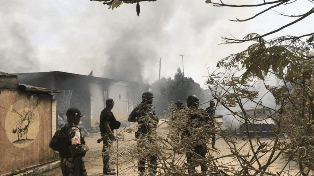 Nigerian regular army soldiers watch buildings burn on Jan 5 to protest military abuse of power in Barkin Ladi. Credit: Masara Kim