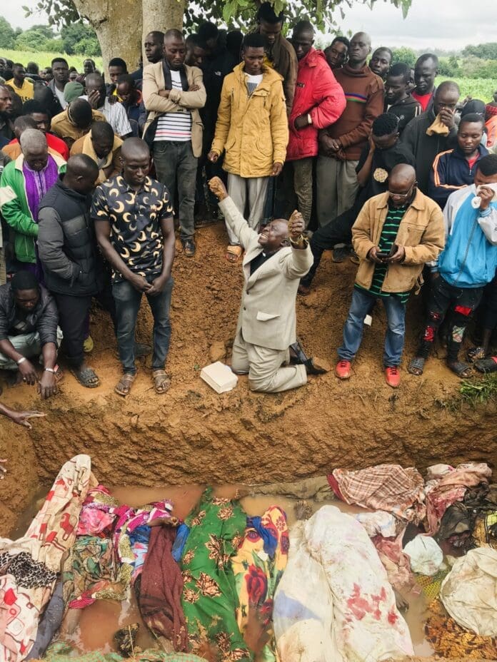 Rev. Ezekiel Dachomo cries to Heaven at a burial ceremony in Barkin Ladi Local Governance Area in August, 2023 after massacre took the lives of 23 members of his congregation. Both Christian and Muslim families inter their departed members within 24 hours of passing. Heavy rains soaked the earth the day before, preventing the grave diggers to obtain the usual depth. Credit: Masara Kim for TruthNIgeria.