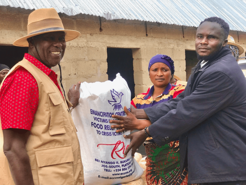 Chibum Sagam (Right) stretches his hands to receive a bag of rice from a representative of Christian Solidarity International in Bokkos on August 3. Credit: Masara Kim.