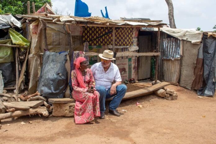 Settlement sponsor Mike Arnold sitting down with Ms Hanatu Ango in front of her house at the New Kuchingoro Camp before it was demolished. credit: Mike Odeh James.