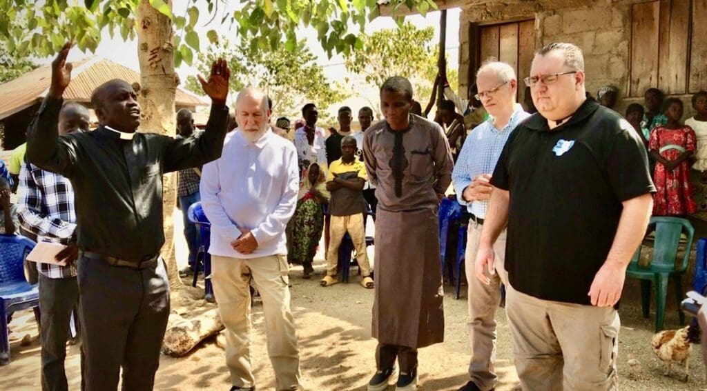 A pastor in Kutara, a makeshift village for IDPs, prays for Judd Saul and his team from Equipping the Persecuted after receiving a cow donation. Credit: Masara Kim
