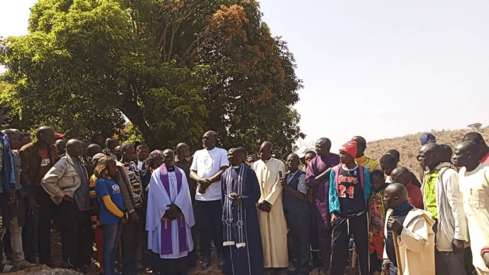Rev. Ayuba Kasa, center, holding bible,  presided at the funeral for the martyrs on Monday. 