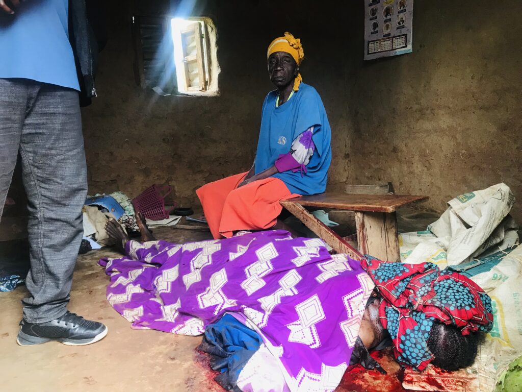 An elderly woman sits helplessly beside her daughter's corpse in Riyom on July 15.