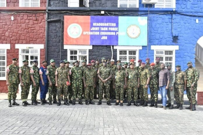 Major General Folusho Oyinlola, the General Officer Commanding 3 Division of the Nigerian Army and Commander of the Joint Task Force Operation Enduring Peace (JTF OPEP), stands (center, holding a cane) with 17 newly decorated OPEP soldiers during their decoration ceremony at the Operation Enduring Peace Multipurpose Hall in Jos. Picture Courtesy: Nigerian Military.