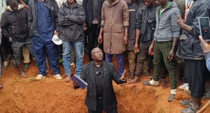 Rev Ezekiel Dachomo in Grave of Victims of last Sunday's attack on Bokkos Credit: Dachomo's photos